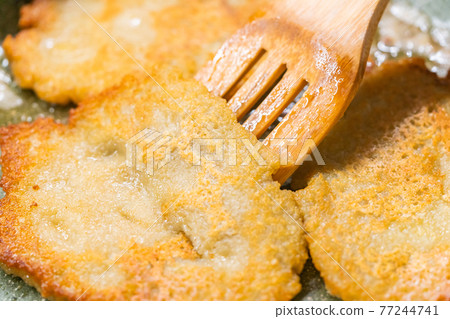 Potato pancakes on green frying pan 77244741