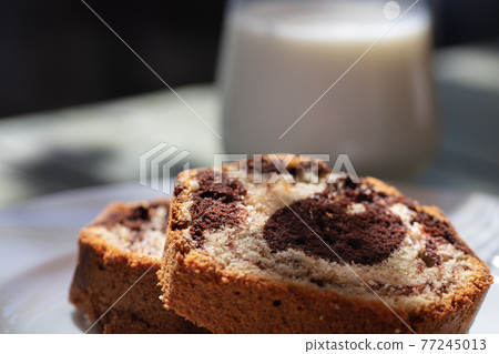 Close up view of Marble cake slice on white plate and wooden table 77245013