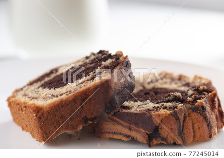 Close up view of Marble cake slice on white plate and wooden table 77245014