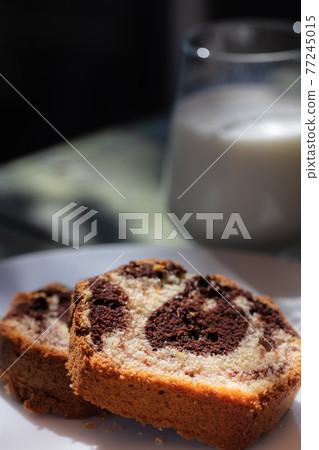 Close up view of Marble cake slice on white plate and wooden table 77245015
