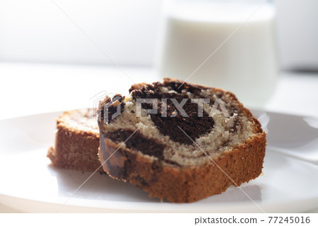 Close up view of Marble cake slice on white plate and wooden table 77245016