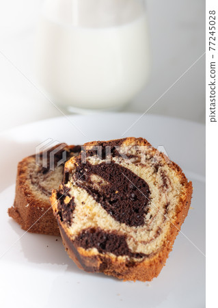 Close up view of Marble cake slice on white plate and wooden table 77245028