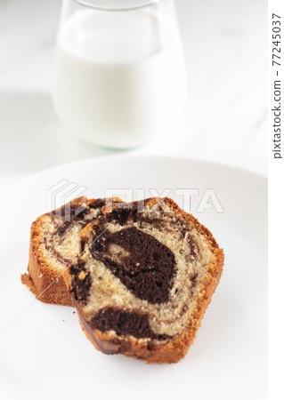 Close up view of Marble cake slice on white plate and wooden table 77245037