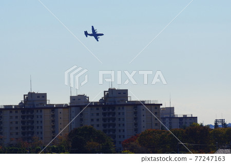 Transport plane flying low in the city 77247163