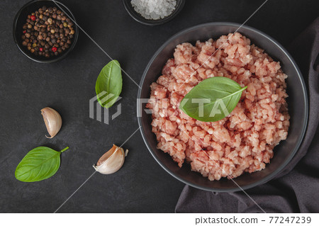 Raw minced meat in bowl on black table Raw minced meat in bowl on black table 77247239