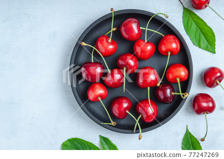 Cherry with leaf on plate and water dropsand on grey stone table 77247269