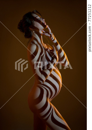 Naked pregnant woman in studio with stripes shadows on body from light 77251212