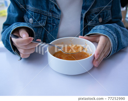 A woman drinking soup 77252990