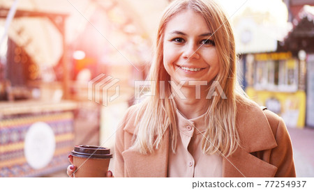 Young blonde with a cup of coffee. Woman at the food court. Glare of the sun Young blonde with a cup of coffee. Woman at the food court. Glare of the sun 77254937