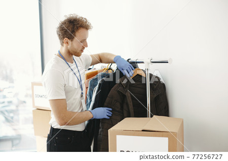 Volunteer guy packs boxes with a humanitarian help 77256727
