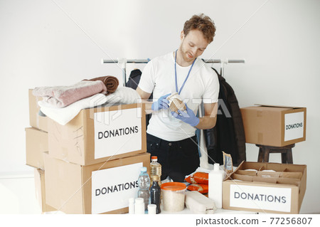 Volunteer guy packs boxes with a humanitarian help 77256807
