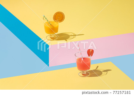 Glasses of orange and strawberry juice with pieces of fruit placed on geometric shapes Glasses of orange and strawberry juice with pieces of fruit placed on geometric shapes 77257181