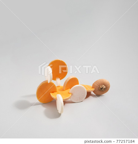 Abstract composition made of sliced butternut squash and white radish isolated on grey background. Abstract composition made of sliced butternut squash and white radish isolated on grey background. 77257184