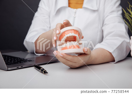 Doctor dentist holds a model of jaw in hand Doctor dentist holds a model of jaw in hand 77258544