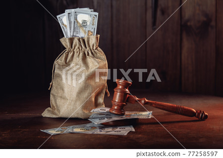 Money bag with dollar banknotes and judge's gavel. Litigation, dispute resolution, conflict of interest settlement 77258597