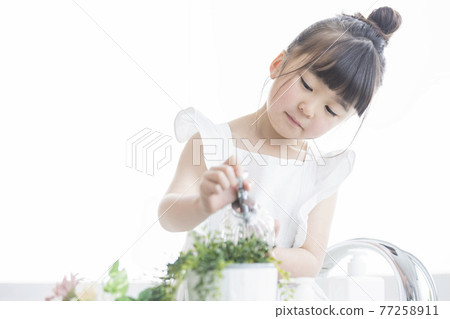 Girl watering foliage plants Girl watering foliage plants 77258911