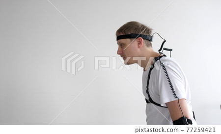 athletic man with beard wears motion capture suit with sensors headset moving in virtual reality taking something and looking at his hands excited experience cyber space online 77259421