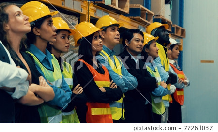 Large group of factory worker standing together in warehouse or storehouse 77261037