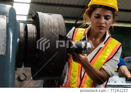 Skillful factory woman worker do machine job in manufacturing workshop Skillful factory woman worker do machine job in manufacturing workshop 77261237