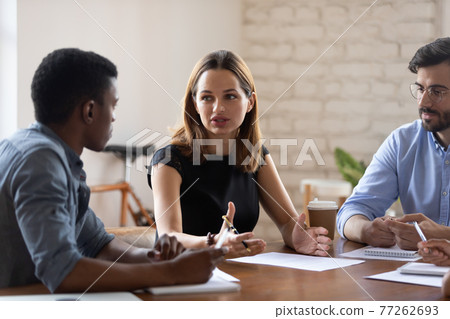 Serious young business lady discussing project with mixed race colleagues. Serious young business lady discussing project with mixed race colleagues. 77262693