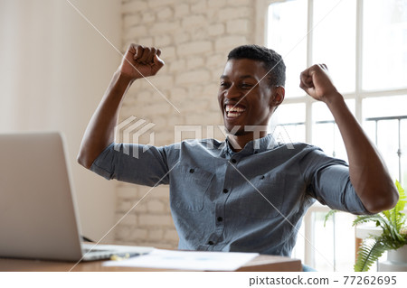 Overjoyed young african american man celebrating online success. Overjoyed young african american man celebrating online success. 77262695