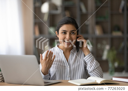 Overjoyed Indian woman talking on phone, hearing good news Overjoyed Indian woman talking on phone, hearing good news 77263020