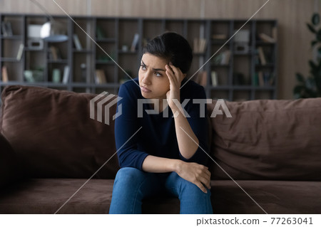 Thoughtful unhappy Indian woman lost in thoughts, looking to aside Thoughtful unhappy Indian woman lost in thoughts, looking to aside 77263041