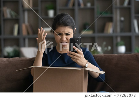Dissatisfied angry Indian woman using phone, dissatisfied by online order Dissatisfied angry Indian woman using phone, dissatisfied by online order 77263078