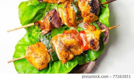 Grilled skewers with chicken, zucchini, mushrooms, peppers and onions served on iceberg lettuce 77263851
