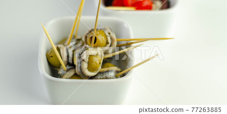 The traditional Spanish appetizers of olives, tomatoes and anchovies in a white ceramic bowls The traditional Spanish appetizers of olives, tomatoes and anchovies in a white ceramic bowls 77263885