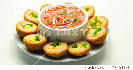 Mini scotch eggs with tomato sauce served on the white ceramic plate 77263986