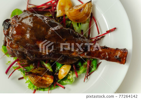 Delicious Lamb shank with red wine and rosemary gravy served on the mixed leaf salad Delicious Lamb shank with red wine and rosemary gravy served on the mixed leaf salad 77264142