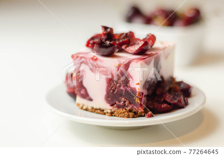 Japanese cheesecake with cherry sauce and fresh cherries on the ceramic plate and red background 77264645