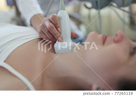 Doctor conducts ultrasound examination of patient thyroid gland 77265119