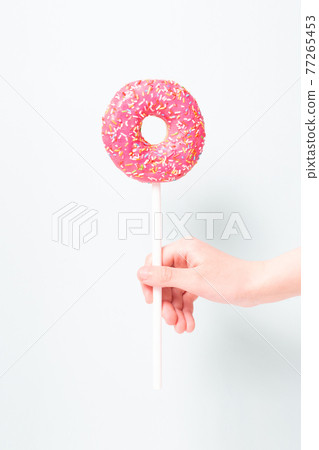 Pink donut in child's hand like lollipop. 77265453