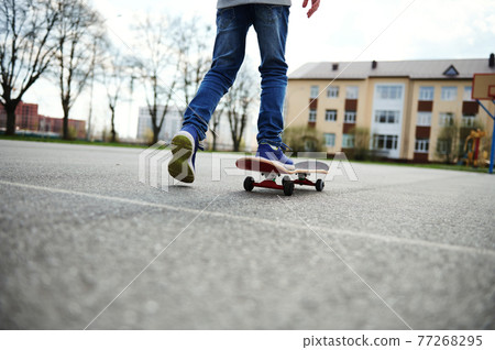 View from the back of skateboarder legs. Kid riding skateboard outdoor. Concept of leisure activity, sport, extreme, hobby. View from the back of skateboarder legs. Kid riding skateboard outdoor. Concept of leisure activity, sport, extreme, hobby. 77268295