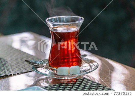 Closeup of cup of Turkish tea with sugar and spoon Closeup of cup of Turkish tea with sugar and spoon 77270185