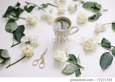 A cup of matcha tea and roses on white background. Flatlay, top view 77271783