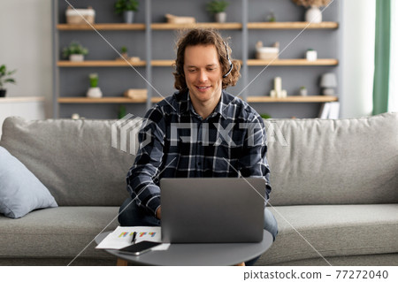 Freelancer Guy Video Calling Via Laptop Wearing Headset At Home Freelancer Guy Video Calling Via Laptop Wearing Headset At Home 77272040