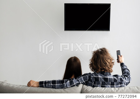Family Watching TV Sitting On Couch At Home, Rear View 77272094