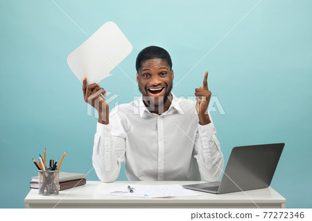 Excited black male worker having creative idea holding speech bubble above his head against blue studio background Excited black male worker having creative idea holding speech bubble above his head against blue studio background 77272346