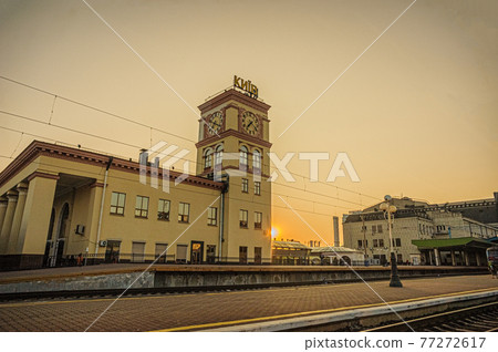 Suburban railway station building with clock tower and Kyiv-Pasazhyrskyi central railway station in the rays of the rising sun. Kyiv, Ukraine Suburban railway station building with clock tower and Kyiv-Pasazhyrskyi central railway station in the rays of the rising sun. Kyiv, Ukraine 77272617