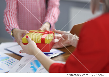 Businesswoman gives gift to colleague at workplace. 77272629