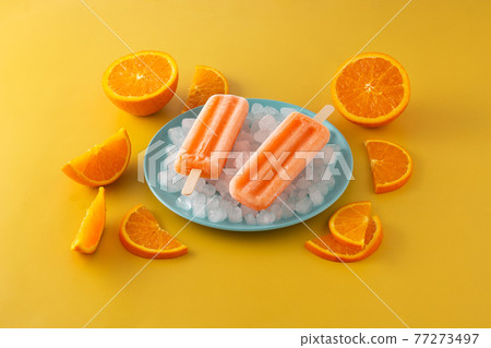 Orange popsicles on blue plate Orange popsicles on blue plate 77273497