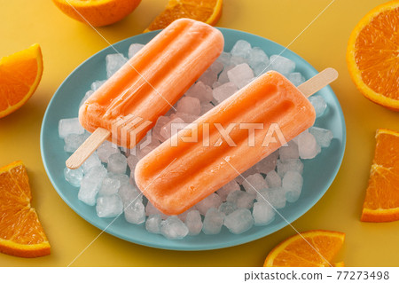 Orange popsicles on blue plate Orange popsicles on blue plate 77273498