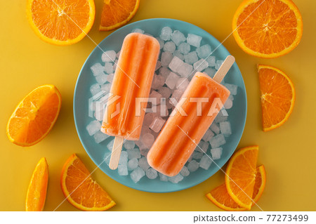 Orange popsicles on blue plate Orange popsicles on blue plate 77273499