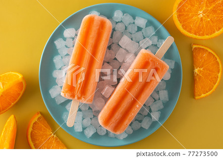 Orange popsicles on blue plate Orange popsicles on blue plate 77273500