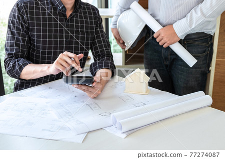 Architects or engineering team consulting and analyzing working on objects tools and construction drawings inspection planning new architectural project on blueprint and model house in modern office 77274087