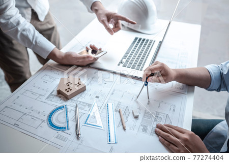 Team of architects or engineering consulting and analyzing working on objects tools and construction drawings inspection, discussing planning new architectural project on blueprint and model house 77274404