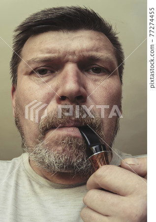 Unusual portrait of a bearded man with a smoking pipe in his mouth. 77274455